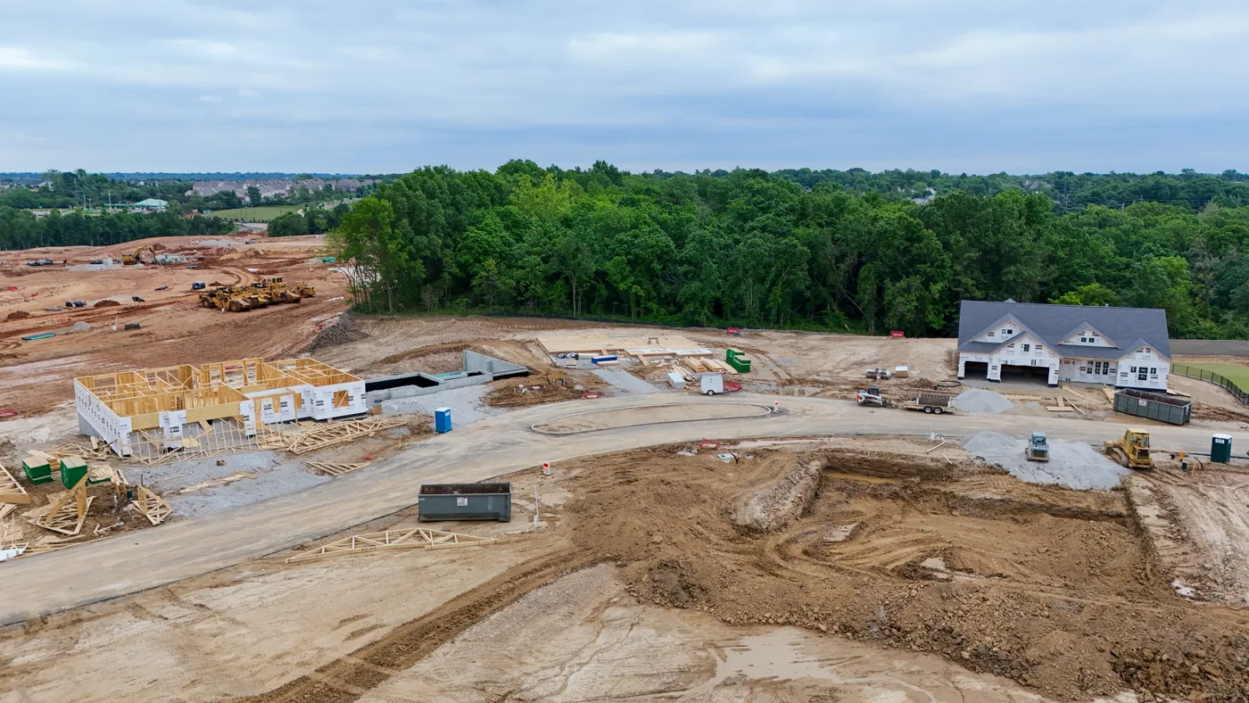 Aerial view of The Reserve at Wildwood under construction, showing active homesites, framed homes, and wooded surroundings